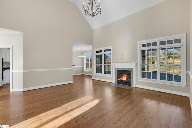 unfurnished living room with a healthy amount of sunlight, a fireplace, hardwood / wood-style flooring, high vaulted ceiling, and crown molding