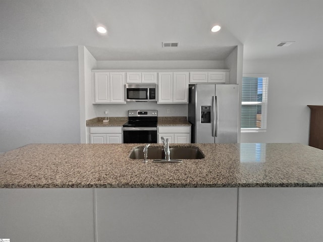 kitchen featuring appliances with stainless steel finishes, a kitchen island with sink, white cabinets, and sink