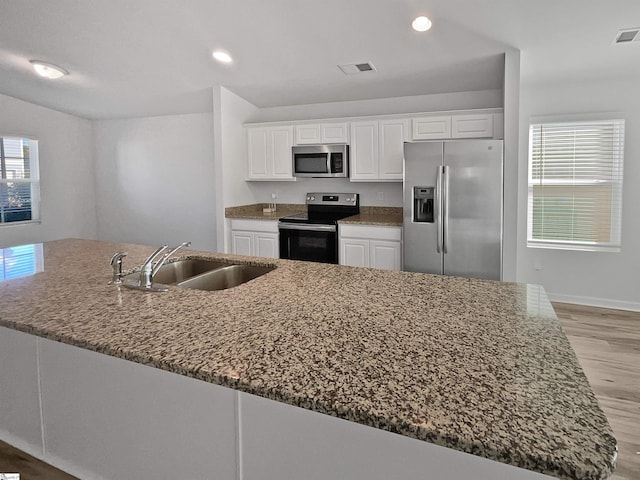 kitchen featuring white cabinets, sink, stone counters, and stainless steel appliances