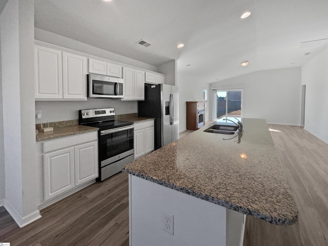 kitchen with vaulted ceiling, appliances with stainless steel finishes, white cabinets, and sink