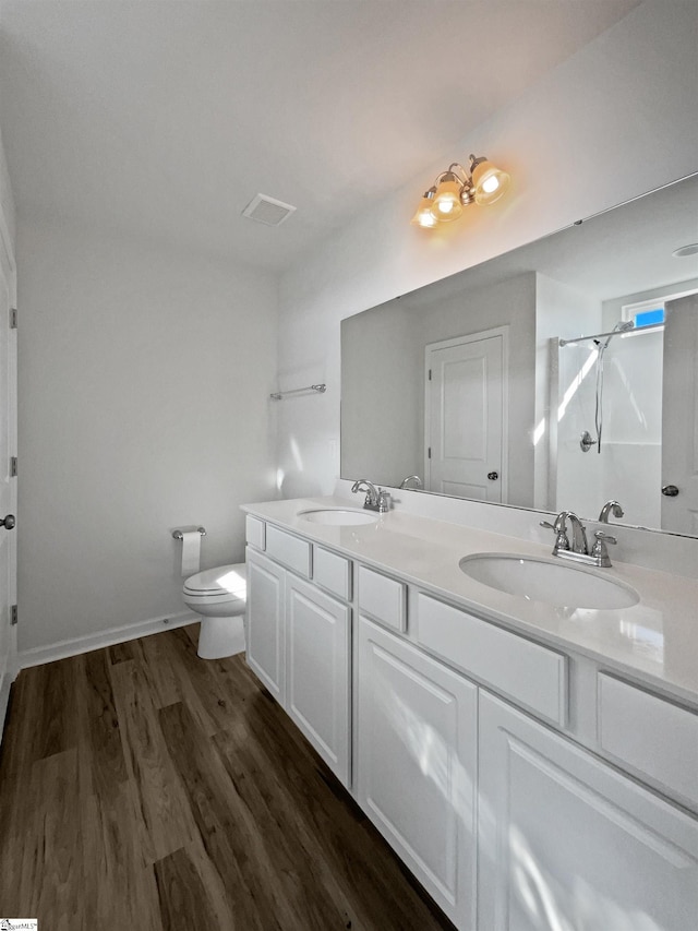 bathroom with vanity, toilet, hardwood / wood-style floors, and walk in shower