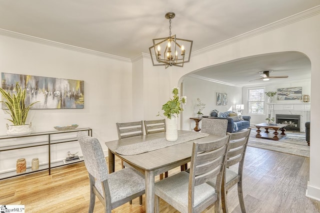 dining area with crown molding, ceiling fan with notable chandelier, and hardwood / wood-style floors