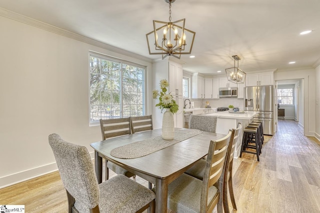 dining space featuring sink, ornamental molding, and light wood-type flooring