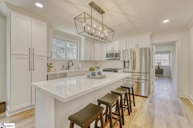 kitchen with white cabinets, appliances with stainless steel finishes, a kitchen island, decorative backsplash, and hanging light fixtures