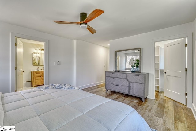 bedroom featuring a spacious closet, ceiling fan, connected bathroom, light wood-type flooring, and a closet