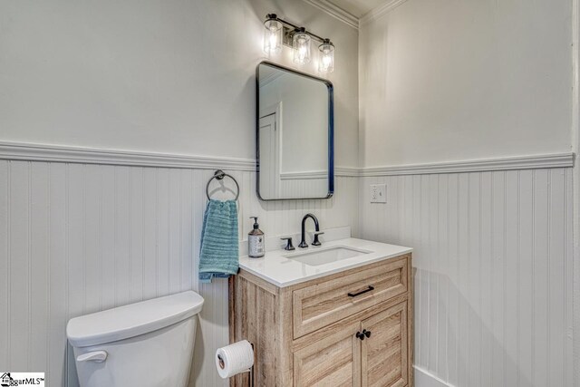 bathroom featuring toilet, vanity, and ornamental molding