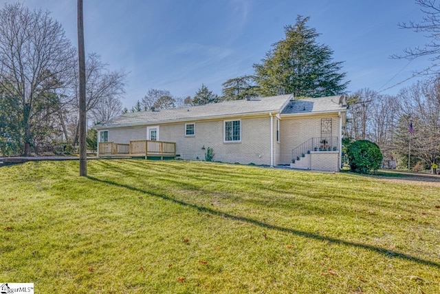 rear view of house featuring a wooden deck and a lawn