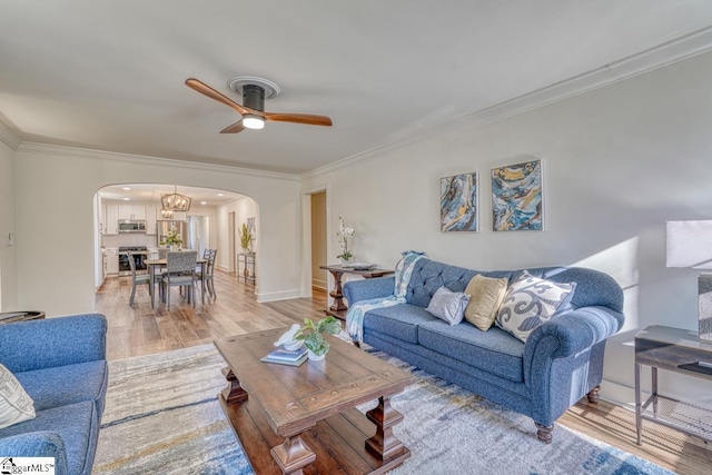 living room with ceiling fan with notable chandelier, ornamental molding, and light wood-type flooring