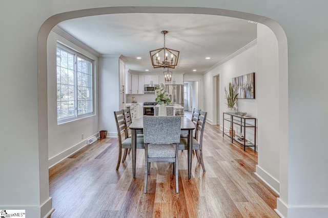 dining room featuring ornamental molding, a chandelier, and light wood-type flooring