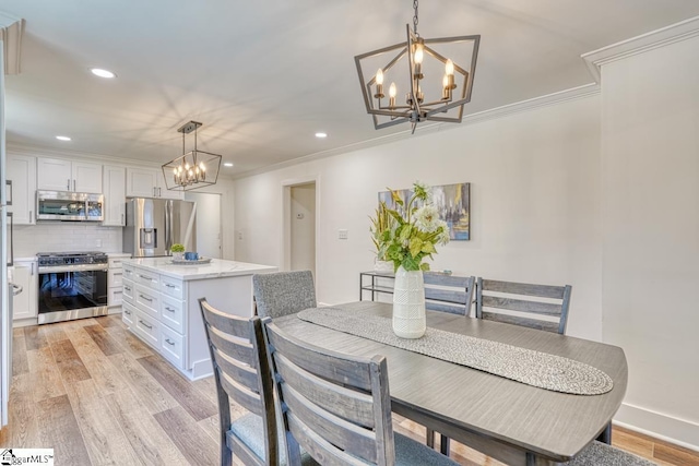 dining area featuring an inviting chandelier, crown molding, and light hardwood / wood-style floors