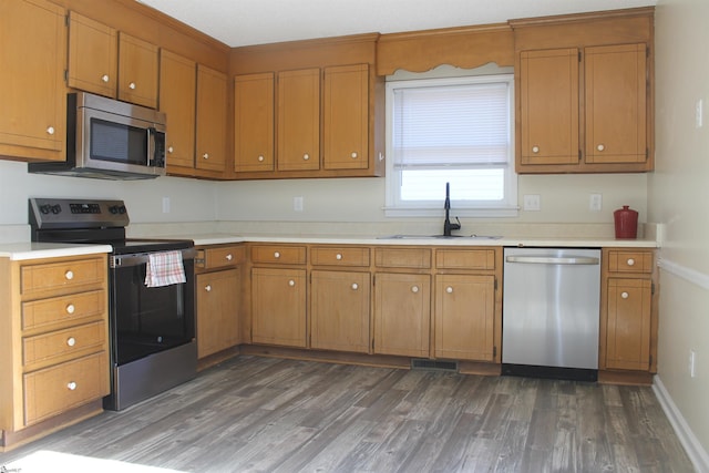 kitchen with dark wood-type flooring, appliances with stainless steel finishes, and sink