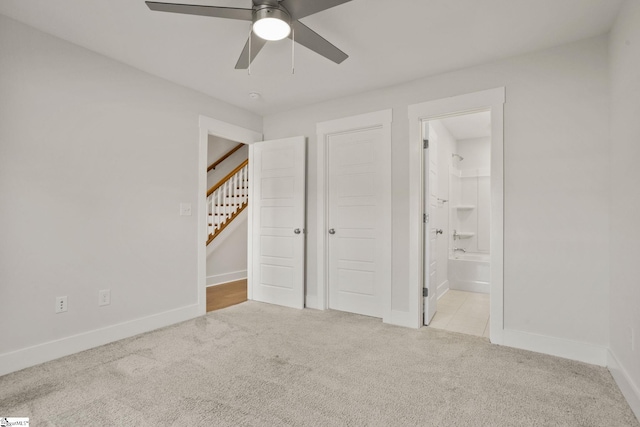 unfurnished bedroom featuring ceiling fan, light colored carpet, a closet, and ensuite bath