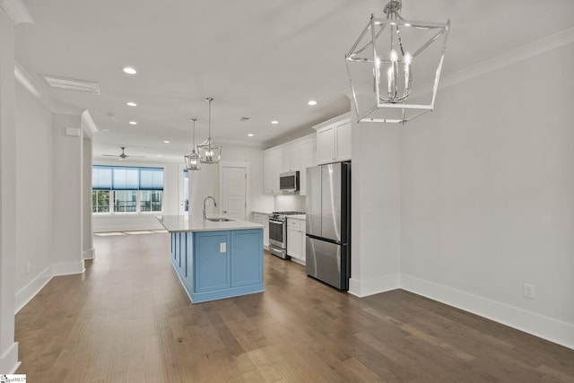 kitchen featuring white cabinets, appliances with stainless steel finishes, decorative light fixtures, sink, and a center island with sink