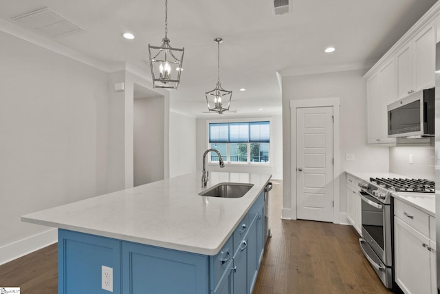 kitchen featuring white cabinetry, stainless steel appliances, an island with sink, sink, and blue cabinetry