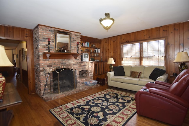 living room featuring a brick fireplace, wood-type flooring, and wood walls