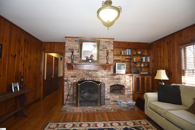 living room with wood-type flooring, built in features, and a fireplace