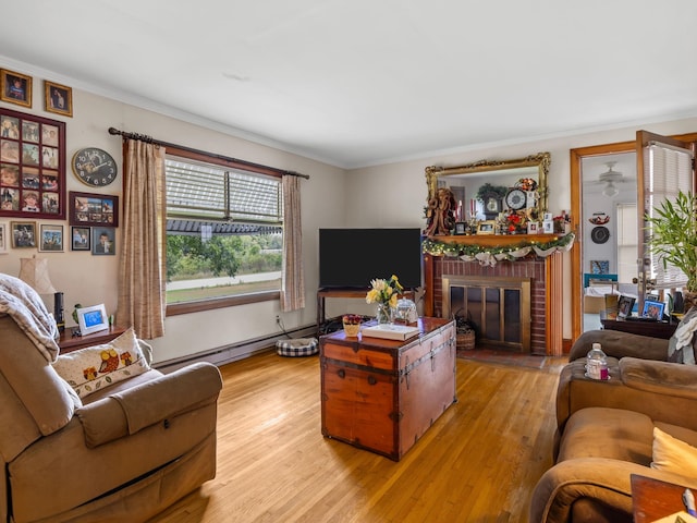 living room with a baseboard heating unit, light wood-type flooring, ornamental molding, and a fireplace