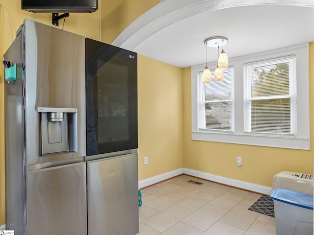 kitchen featuring light tile patterned floors, stainless steel fridge, and hanging light fixtures