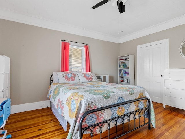 bedroom with ceiling fan, a closet, ornamental molding, and hardwood / wood-style floors