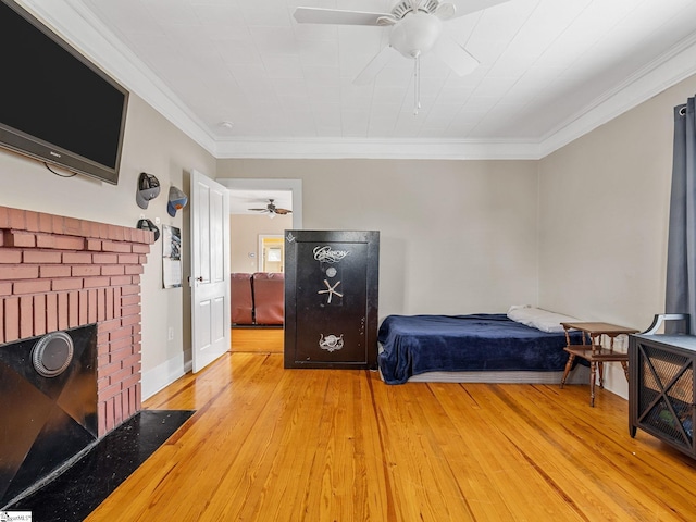 bedroom with ceiling fan, light hardwood / wood-style floors, ornamental molding, and a fireplace