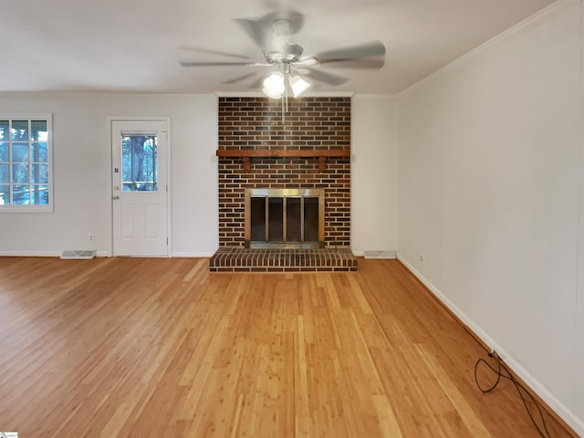 unfurnished living room with ceiling fan, a brick fireplace, and light hardwood / wood-style flooring