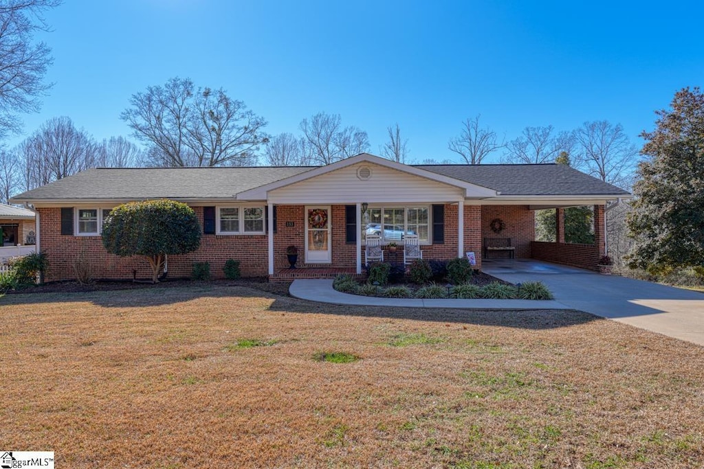 single story home with covered porch, a front lawn, and a carport