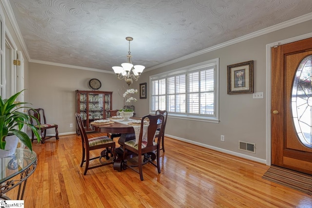 dining space with a chandelier, light wood-type flooring, ornamental molding, and a textured ceiling