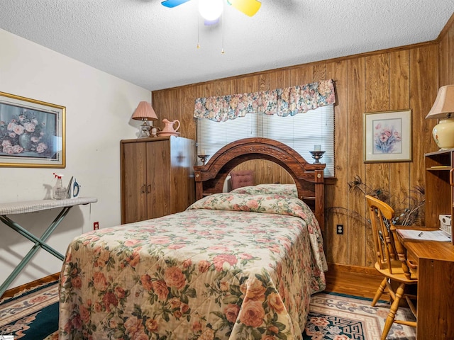 bedroom with a textured ceiling, ceiling fan, and wood walls