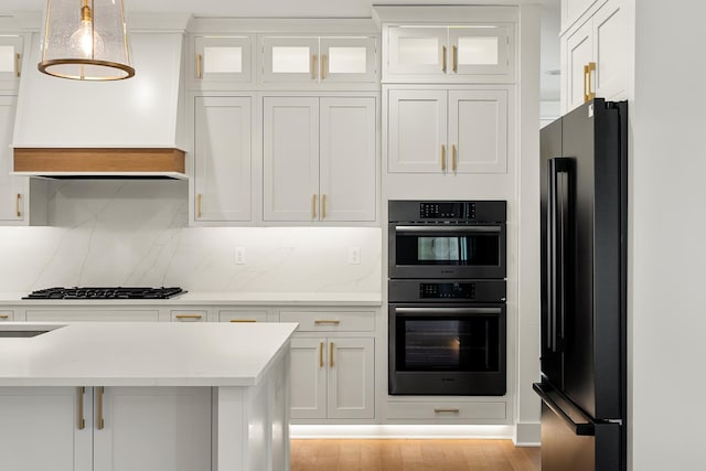 kitchen featuring hanging light fixtures, gas cooktop, white cabinets, and black refrigerator