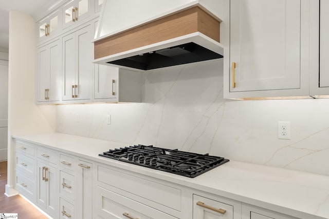 kitchen with white cabinets, black gas cooktop, premium range hood, and tasteful backsplash