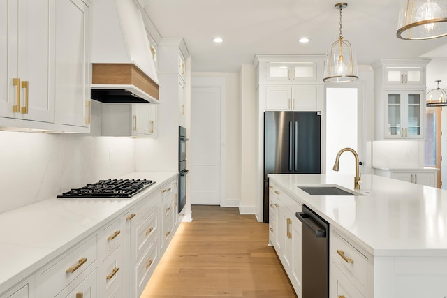 kitchen featuring premium range hood, appliances with stainless steel finishes, hanging light fixtures, white cabinets, and sink