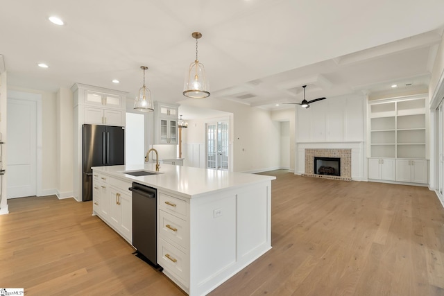 kitchen with stainless steel fridge, an island with sink, ceiling fan, white cabinets, and sink