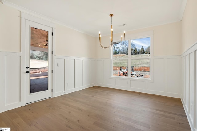 unfurnished dining area featuring a notable chandelier, crown molding, and light hardwood / wood-style floors