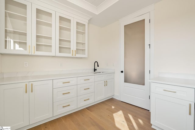 bar featuring white cabinets, sink, and light hardwood / wood-style flooring