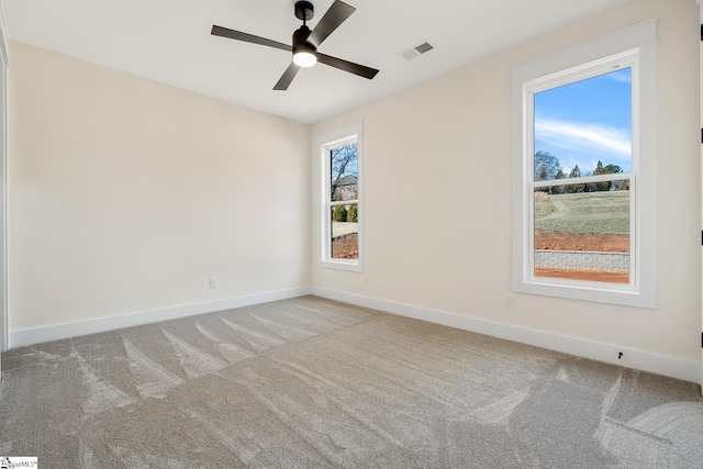 spare room featuring light carpet, ceiling fan, and a wealth of natural light