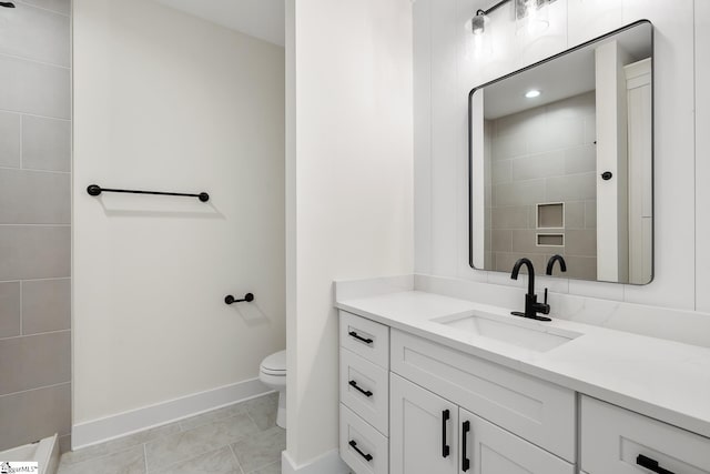 bathroom with toilet, vanity, and tile patterned flooring