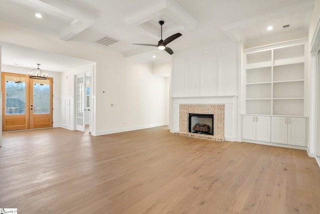 unfurnished living room featuring light hardwood / wood-style floors, coffered ceiling, french doors, ceiling fan with notable chandelier, and built in shelves