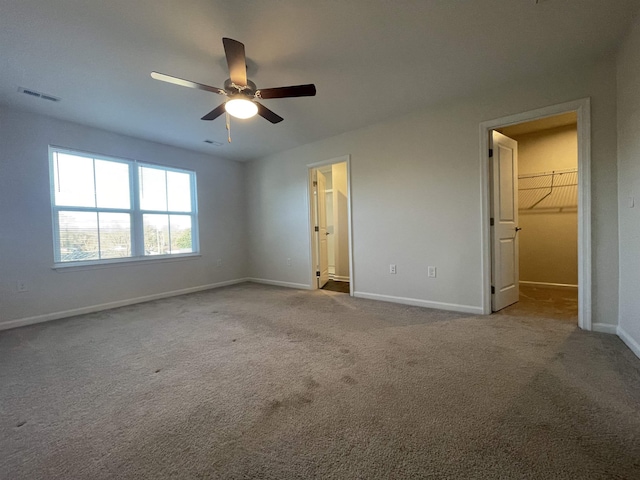 unfurnished bedroom featuring light carpet, ceiling fan, a spacious closet, and a closet