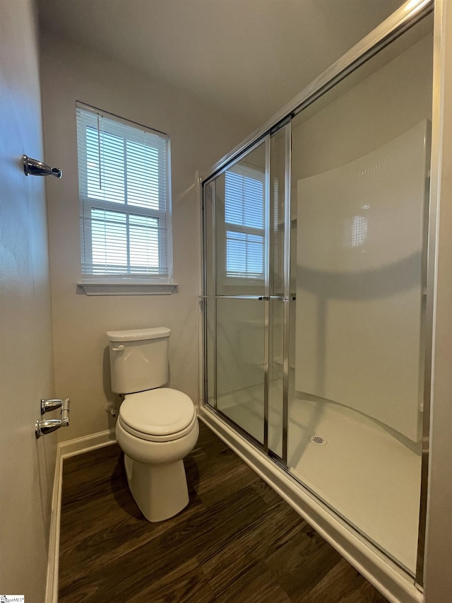 bathroom with toilet, a shower with shower door, and hardwood / wood-style floors