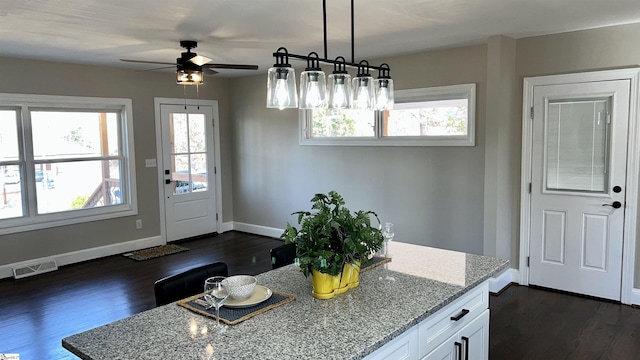 kitchen featuring decorative light fixtures, ceiling fan, dark hardwood / wood-style floors, white cabinets, and light stone counters