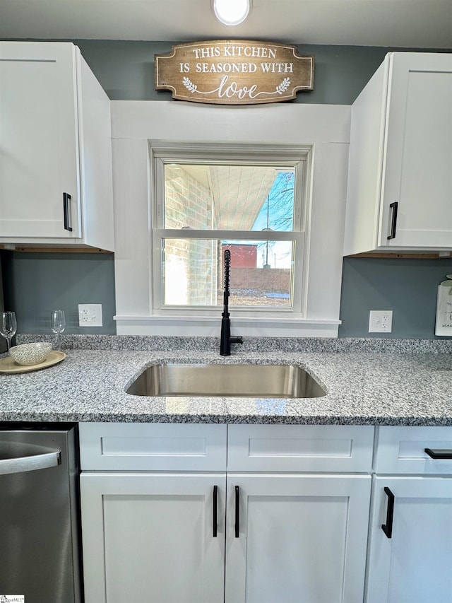 kitchen featuring dishwasher, white cabinets, light stone counters, and sink