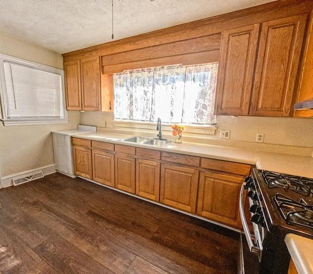 kitchen with a textured ceiling, gas stove, dark hardwood / wood-style floors, and sink