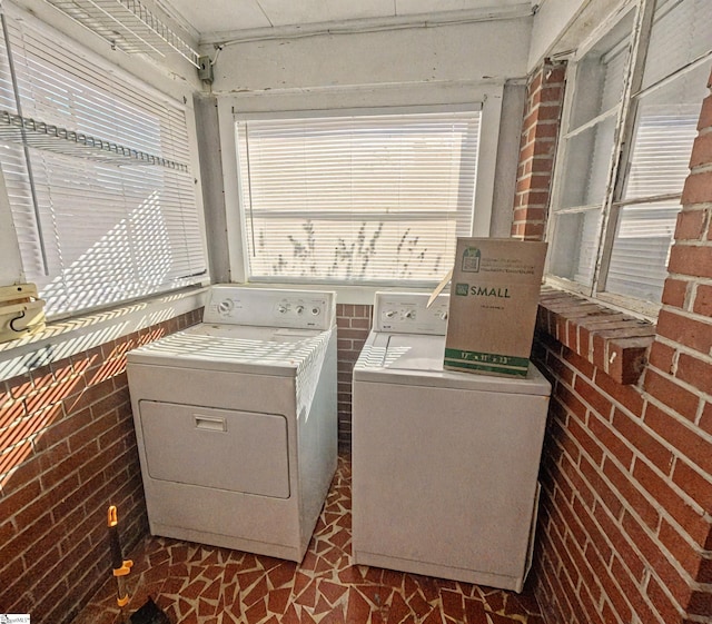 washroom featuring brick wall and washing machine and clothes dryer