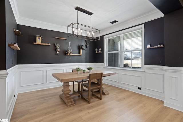 dining room featuring light wood-type flooring, ornamental molding, and a chandelier