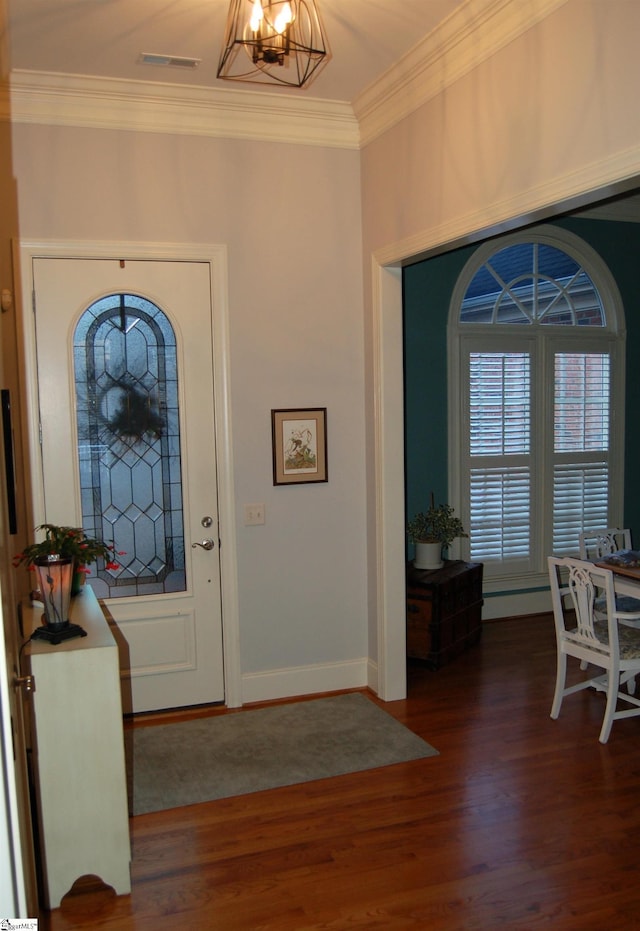 foyer entrance with dark wood-type flooring, crown molding, and a chandelier