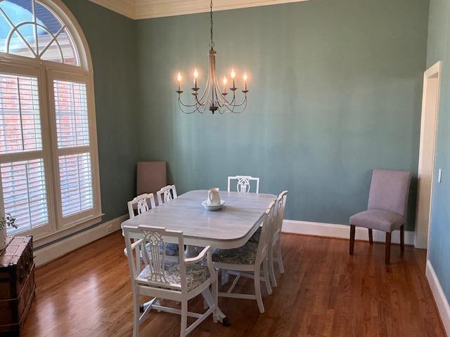 dining space featuring a baseboard heating unit, a notable chandelier, crown molding, and dark hardwood / wood-style floors