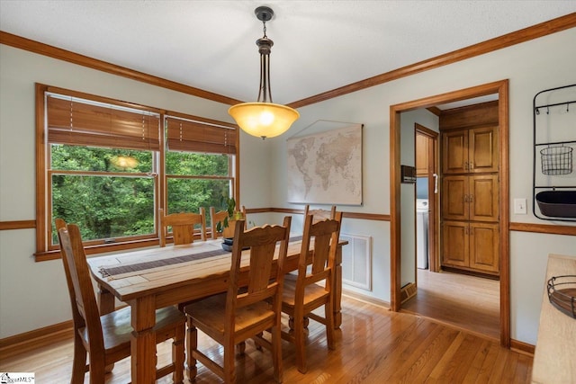 dining room with crown molding and light hardwood / wood-style floors