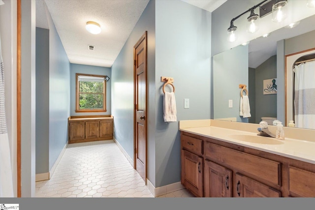 bathroom with a textured ceiling, tile patterned floors, and vanity