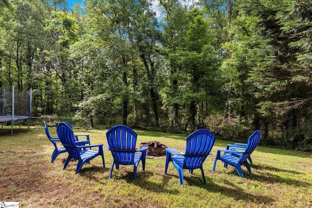 view of yard featuring a trampoline and an outdoor fire pit