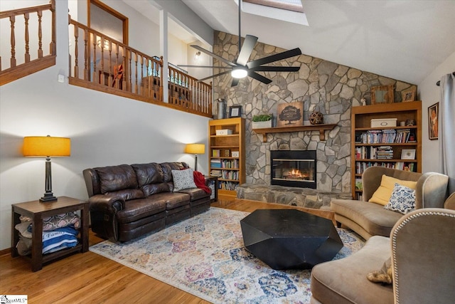 living room with hardwood / wood-style flooring, high vaulted ceiling, ceiling fan, and a fireplace